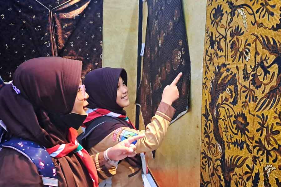 Dua pelajar melihat dari dekat koleksi Pameran Temporer Koleksi Museum 'Wastra Tradisional Jawa Timur dalam Konstelasi Perkembangan Batik Nusantara'