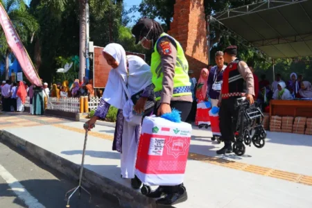 Ramah Lansia, Polisi Beri Layanan Prima untuk Pemberangkatan CJH Situbondo Petugas dari Polres Situbondo membantu seorang lansia calon jamaah haji (foto: Dok Humas Polri)