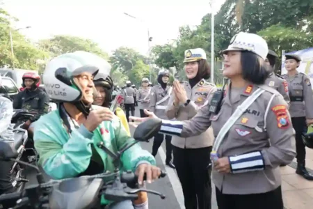 Peringati Hari Jadi ke-77, Polwan Polda Jatim gatur lalu lintas di Surabaya sambil bagikan helm, bunga, dan cokelat kepada pengendara yang tertib.